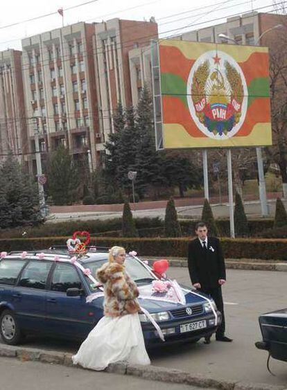 Una pareja de recién casados, en el centro de Tiráspol, frente al escudo de los independentistas.