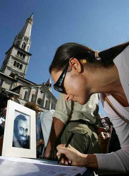 Una mujer firma en el libro de condolencias instalado en el exterior de la catedral de Módena.