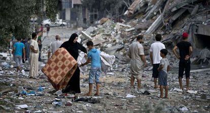 Una mujer lleva sus pertenencias con la ayuda de un niño en Gaza.