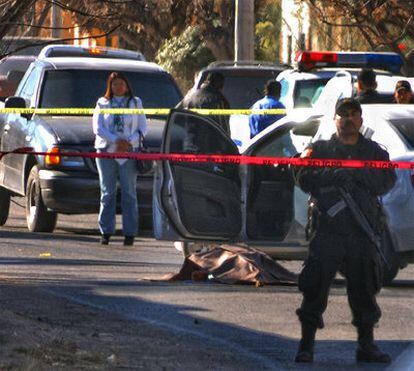 Especialistas forenses recogen información de la escena del crimen, con el cadáver todavía en el suelo.