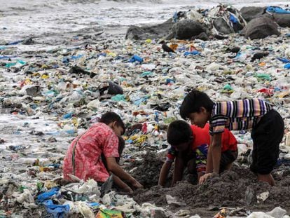 Varios niños juegan entre desechos de comida y plástico cerca de la costa del mar Arábigo, en la playa de Mahim, en Bombay (India)