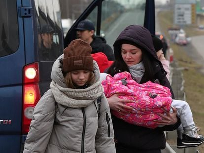 Una mujer sostiene a un niño antes de cruzar la frontera de Ucrania con Polonia por el paso de Dorohusk, el viernes. Decenas de miles de ciudadanos tratan de salir del país hacia Polonia y Hungría.