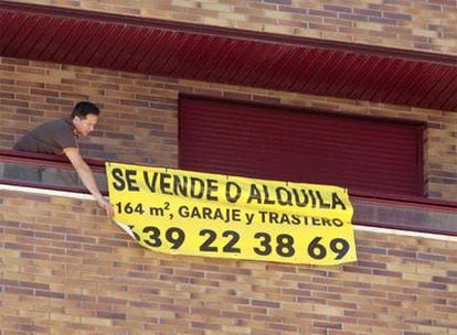 Un propietario coloca un cartel de venta o alquiler en la fachada de su vivienda.