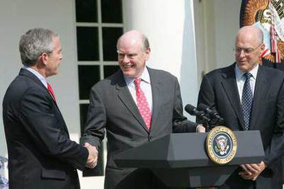 El presidente Bush saluda a John Snow ante la mirada del nuevo secretario del Tesoro, Henry Paulson.