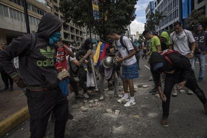 Manifestantes reúnen piedras para lanzar a las fuerzas policiales, después de que Juan Guaidó se declaró presidente interino frente a miles de venezolanos.
