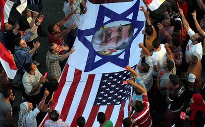Un grupo de manifestantes avanza en la marcha transportando un cartel  con las banderas norteamericana e israel&iacute; con la cara del presidente Morsi.