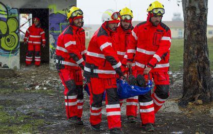 Varios bomberos evacuan a un hipot&eacute;tico herido en el terremoto.