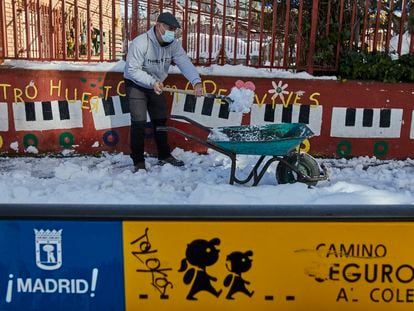 Un familiar colabora en la limpieza del hielo y la nieve en las inmediaciones del colegio Amadeo Vives tras la nevada.