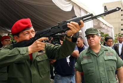 El presidente venezolano, Hugo Chávez, prueba el nuevo modelo de fusil de asalto ruso Kalashnikov, el AK-103, ante el ministro de Defensa, Orlando Maniglia, en junio en Caracas