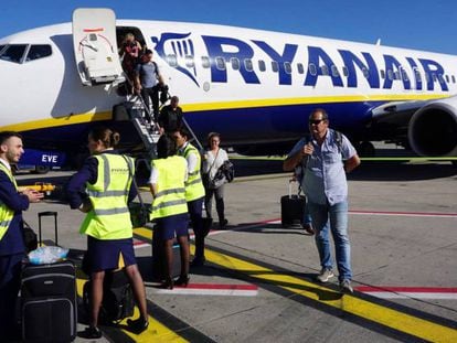 Tripulantes de cabina de pasajeros de Ryanair, a pie de pista, ante un avión de la compañía.