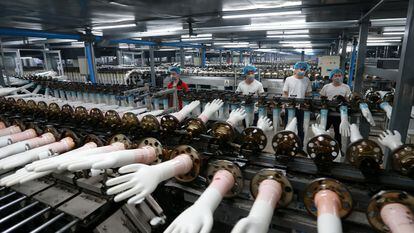 Cadena de producción de guantes de vinilo desechables en una fábrica en China.