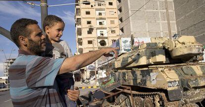 <a href="http://elpais.com/elpais/2016/02/25/album/1456390257_259508.html"><b>FOTOGALERÍA: VIAJE A MISRATA |</b></a> Jalid Shabha mira junto a su hijo los tanques de la avenida Trípoli, en Misrata.