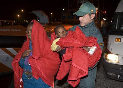 Un guardia civil ayuda a inmigrantes de la patera rescatada en el mar de Alborán a bordo de la cual una mujer dio a luz.