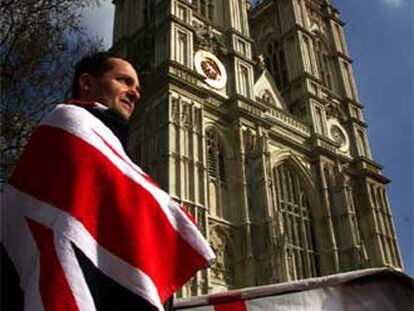 Un ciudadano británico se envuelve en la bandera Union Jack ante la abadía de Westminster.