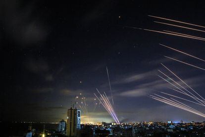 El sistema israelí de defensa de misiles Iron Dome (izquierda) intercepta cohetes (derecha) disparados por el movimiento Hamas hacia el sur de Israel desde Beit Lahia en el norte de la Franja de Gaza, durante la noche del 16 de mayo de 2021.
