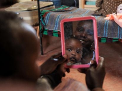Una madre adolescente keniana se mira en el espejo mientras juega con su bebé, en febrero de 2021.