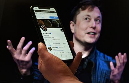 The phone displays Elon Musk's Twitter account, over a photo of him in the background.