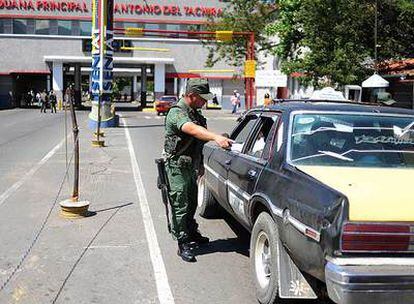 Un miembro de la Guardia Nacional venezolana ordena a un taxista que abra el maletero antes de pasar la frontera en San Antonio, Venezuela