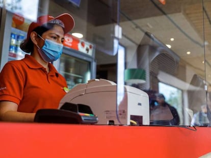 Una empleada de la cadena de pizzerias Telepizza posa tras una mampara de protección en uno de sus establecimientos en Alcobendas, Madrid