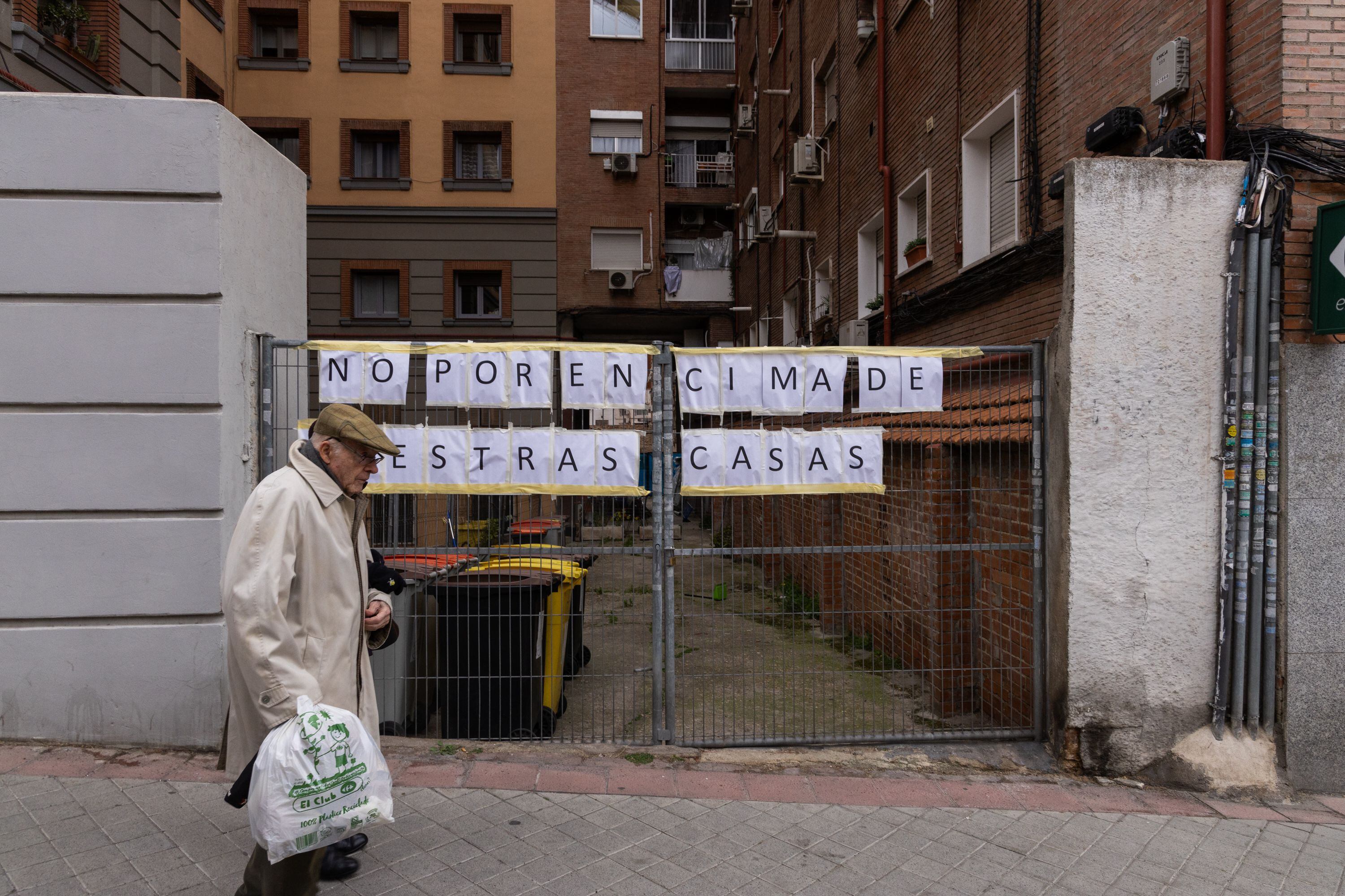 Un hombre pasa por delante de los edificios afectados por la operación de transporte de maquinaria, en la calle Cavanilles de Madrid.