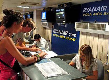 Pasajeros en el aeropuerto de Girona facturan sus billetes en un mostrador de Ryanair.