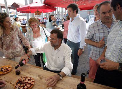 Rajoy se sirve vino y habla con Ana Pastor en la fiesta del PP en Silleda. Detrás de él, de izquierda a derecha, Feijóo, José Crespo y Rafael Louzán.