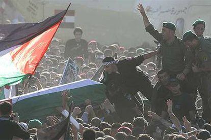 Agentes de las fuerzas de seguridad trasladan el féretro de Arafat entre una marea humana incontrolada.
