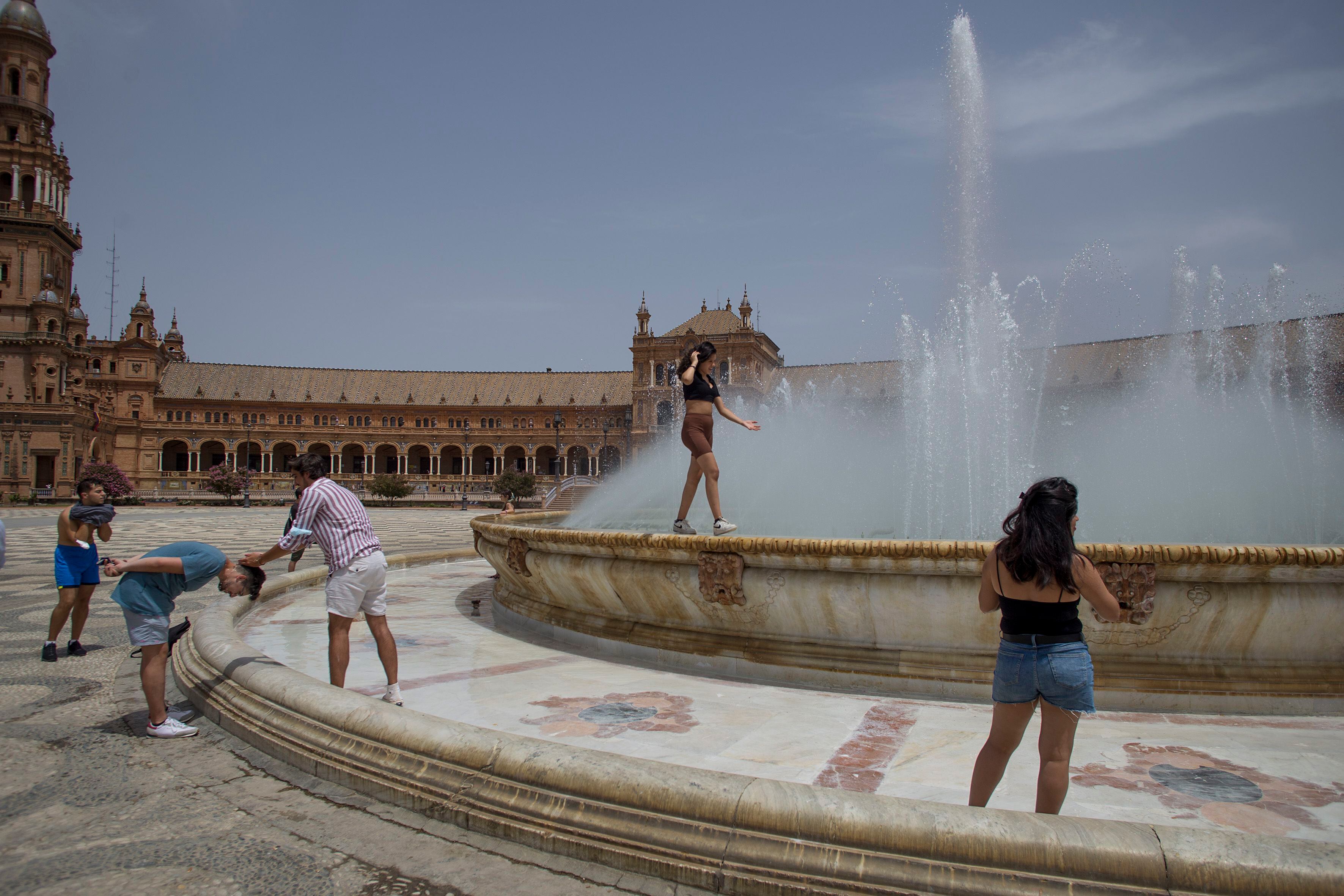 Varios ciudadanos se refrescan en la fuente central de la Plaza de España en Sevilla.