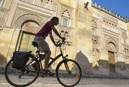 Un ciclista a su paso por la fachada oriental de la mezquita de Córdoba.