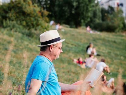 Un hombre lee en el Mauerpark de Berlín con la torre de televisión de Alexanderplatz al fondo.