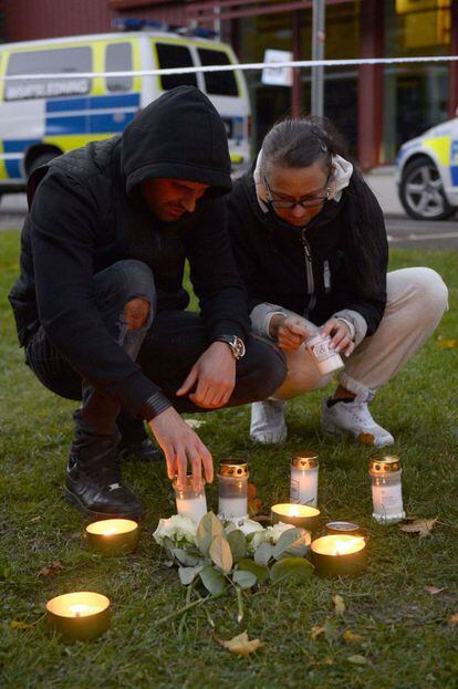 Además de los dos fallecidos, al menos dos personas fueron heridas. En la imagen, dos personas encienden velas en las afueras del colegio en Trollhättan, Suecia.