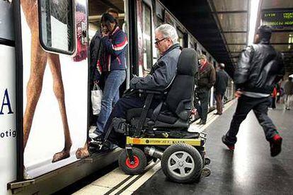 Un hombre en silla de ruedas lucha contra las barreras para entrar en el metro de Barcelona.