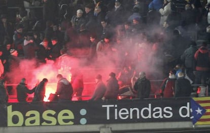 Aficionados del Madrid reciben una bengala lanzada por los del Barça, el 26 de febrero en el Camp Nou