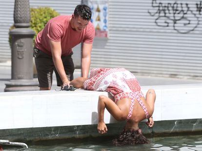 Dos turistas se refrescan en una fuente del centro de Sevilla, este lunes.