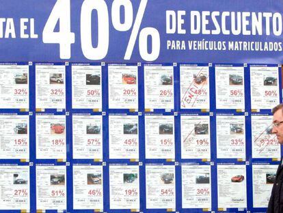 Un concesionario de vehículos con un cartel anunciando grandes decuentos por la compra de turismos y todoterrenos. 