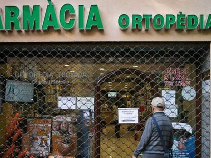 Un hombre lee un cartel en una farmacia de guardia en Barcelona.