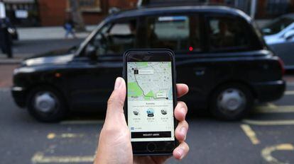 Una mujer sostiene un tel&eacute;fono con la App de Uber en Londres