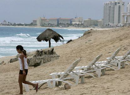Una mujer pasea por las playas vacías de Cancún.