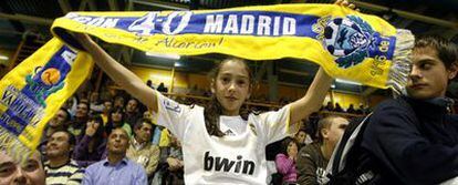 Una niña con la camiseta del Madrid levanta la bufanda del Alcorcón en el polideportivo Los Cantos, donde los aficionados pudieron seguir el partido del Bernabéu.