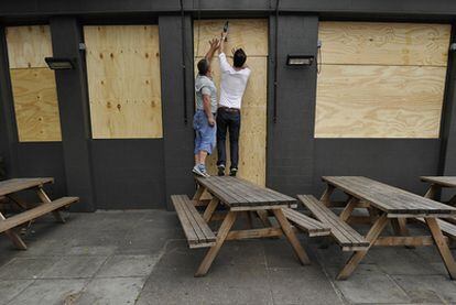 Empleados de un pub de Londres clavan planchas de madera en puertas y ventanas.