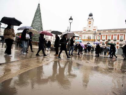 Los paseantes sortean un charco en la Puerta del Sol, este lunes.