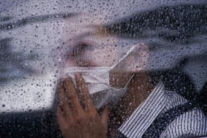 Un hombre con mascarilla en un automóvil durante un día lluvioso en Shanghái (China).