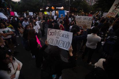 A young woman holds a sign with the phrase "Gentrification = Colonization" during a protest in Mexico City against gentrification on November 17, 2022.