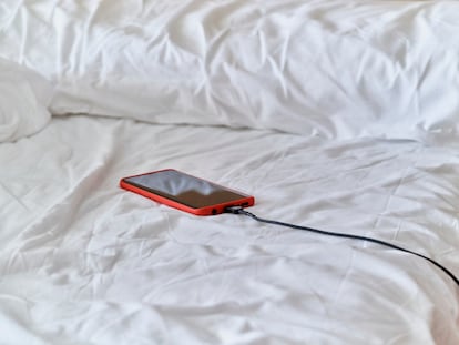 Un teléfono móvil cargando sobre una cama.