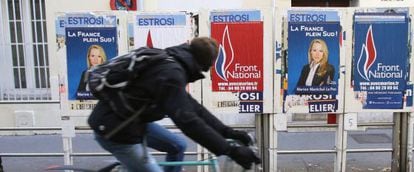 Un ciclista pasa en Marsella delante de varios carteles electorales de la candidata del Frente Nacional, Marion Marechal-Le Pen. 