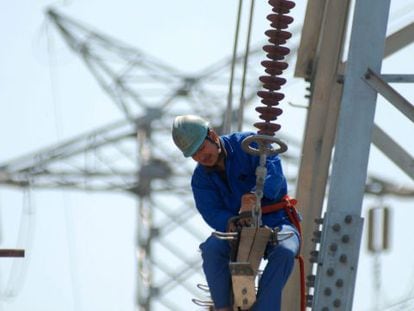 Un trabajador instala nuevas l&iacute;neas de alto voltaje en una torre de electricidad.