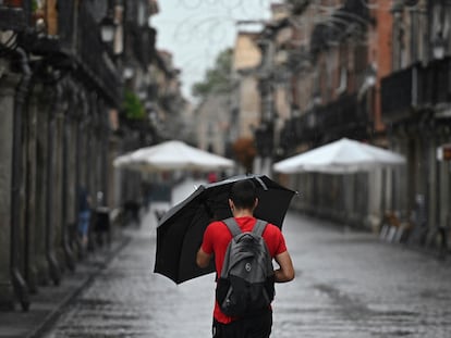 Un hombre se protege de la lluvia que cae este miércoles en Alcalá de Henares.