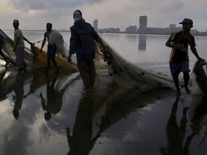 Pie de Foto: Un grupo de pescadores paquistaníes arrastran sus redes en una playa de Karachi, Pakistán