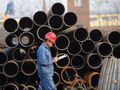 Un trabajador pasa junto a varias tuber&iacute;as de acero en un almac&eacute;n en Shenyang, noreste de China.