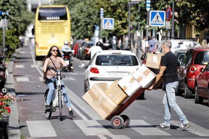 Una mujer circula con una bicicleta de Bicimad por el carril bici de la calle Mayor.
